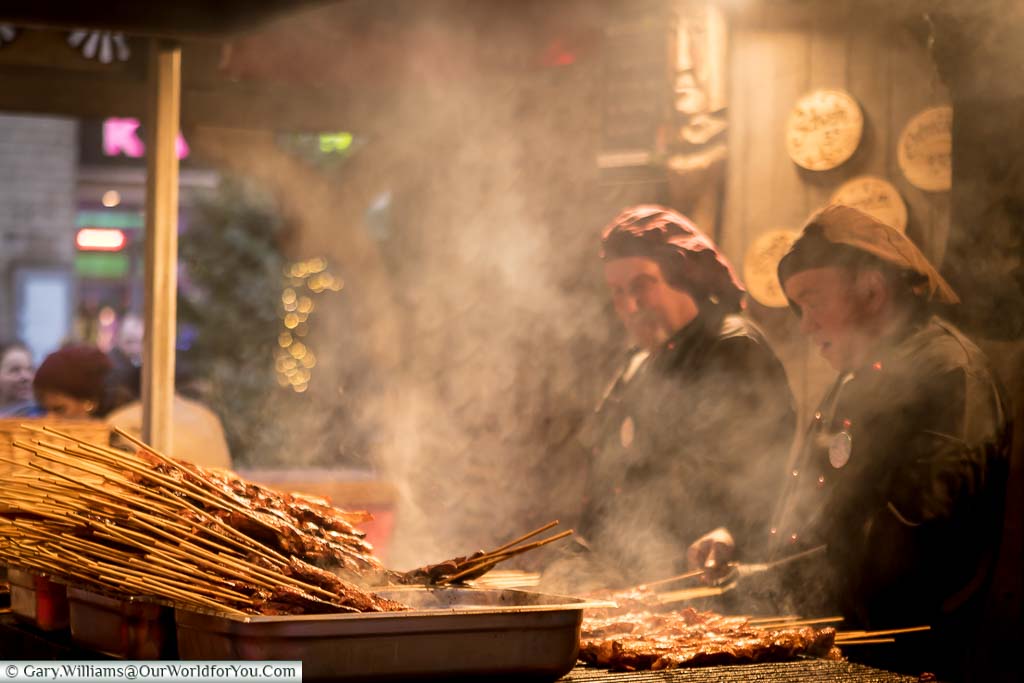 Metre long meat skewers being prepared on a smokey grill in Cologne, Germany