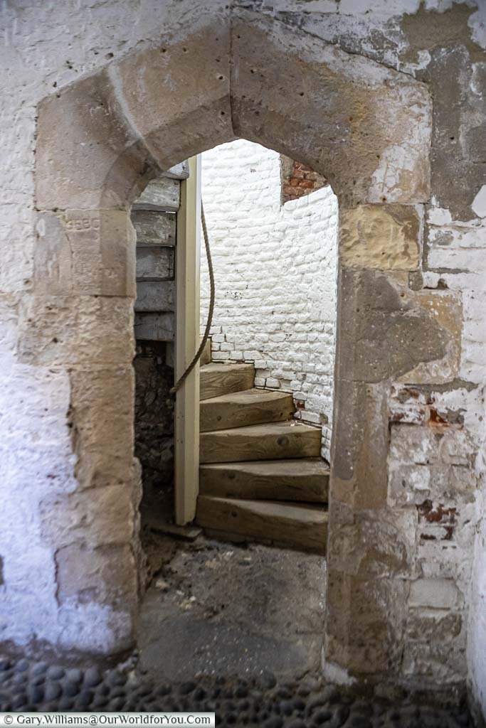 A heavy stone archway leading to a spiral staircase within Deal Castle