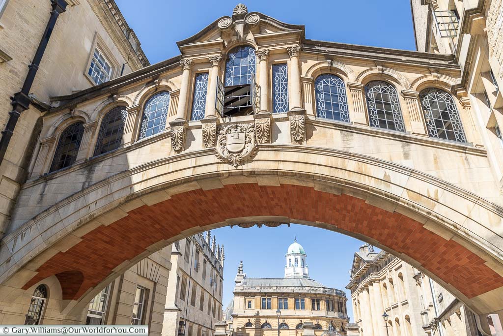 A close-up view of the Hertford Bridge, also known as the Bridge of Sighs, with the Sheldonian Theatre in the background.
