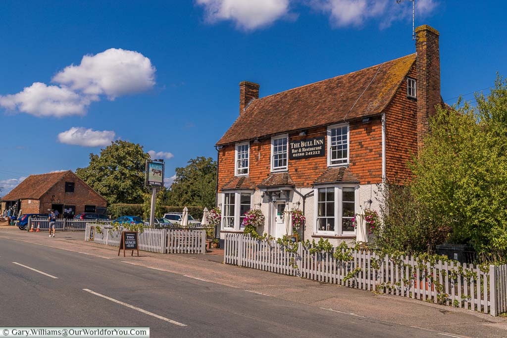The Bull Inn, a traditional Kentish country pub with the picket fence and tables and chairs in its garden in Rolvenden, Kent