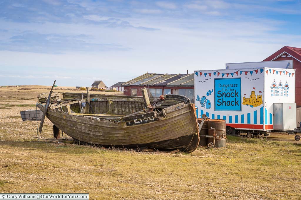 The Dungeness Fish Hut Snack Shack hiding behind a weather-beaten fishing boat on the beach at Dungeness