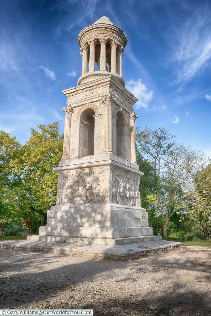 A free standing Roman white stone mausoleum just outside St Remy de Provence set against a blue Sky with wispy white clouds.