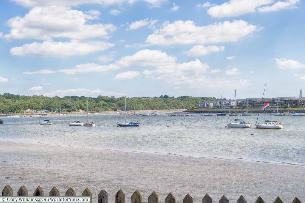 A view over the River Medway, at low tide, as it bends around Chatham with yachts moored up.