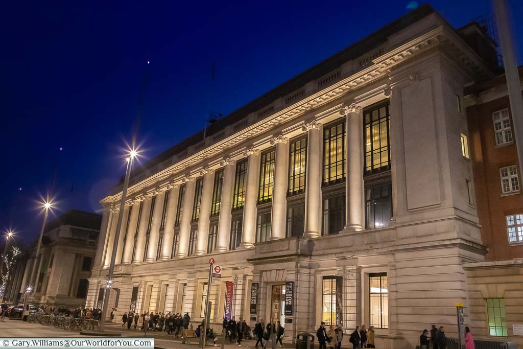 The floodlit grand Victorian facade to the Science Museum after dark under a deep blue sky