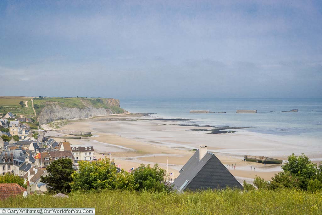 The shoreline and bay of Arromanches from on high.  You can view, both on the beach, and out to sea, the remains of the 'temporary' mulberry harbour constructed for the D-Day landings.