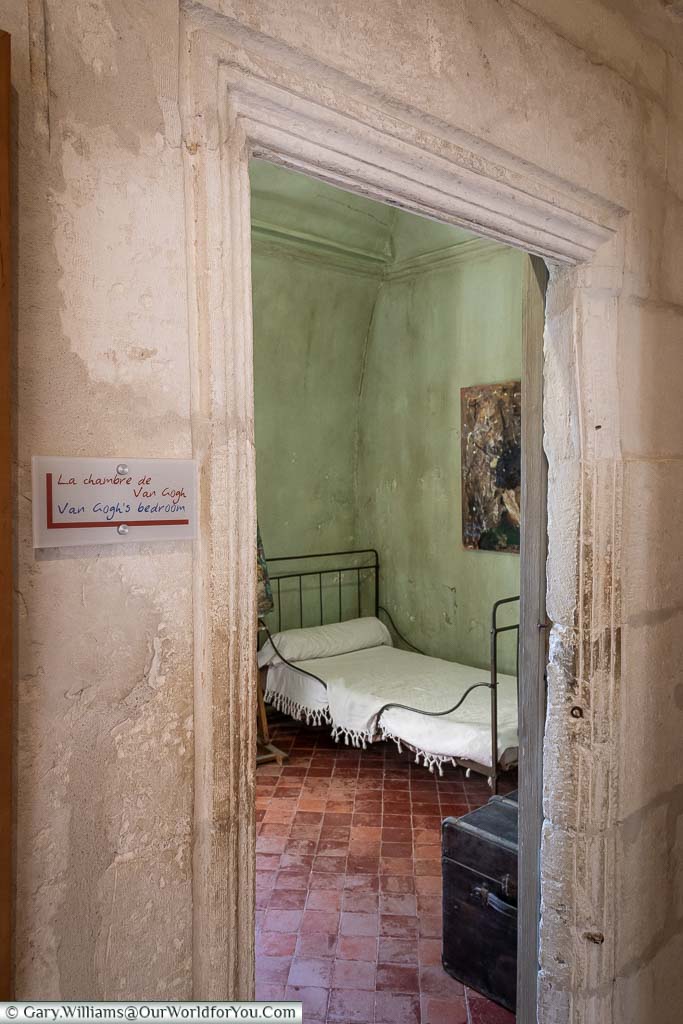 The view through the doorway into Vincent Van Gough’s room in Saint-Paul-de-Mausole. The basic looking room painted in a pile green features a small iron bed.