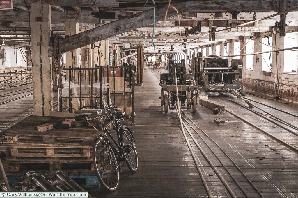 Inside the Ropery at the Historic Chatham Dockyard where an old bike, the only transport to cover the distance, rests against the equipment.