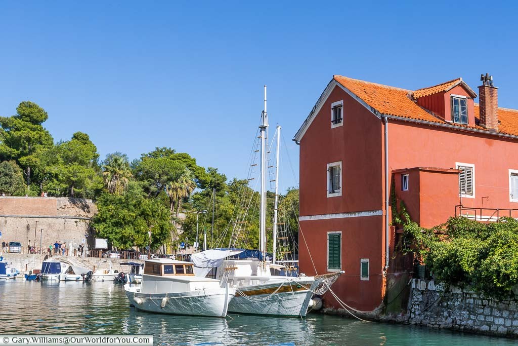 Two white sailing boats mooring in the small picturesque port of Fosa in Zadar.