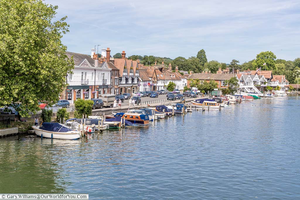 A number of small boats moored up at the Thames Riverside in Henley-on-Thames on a bright summers day.