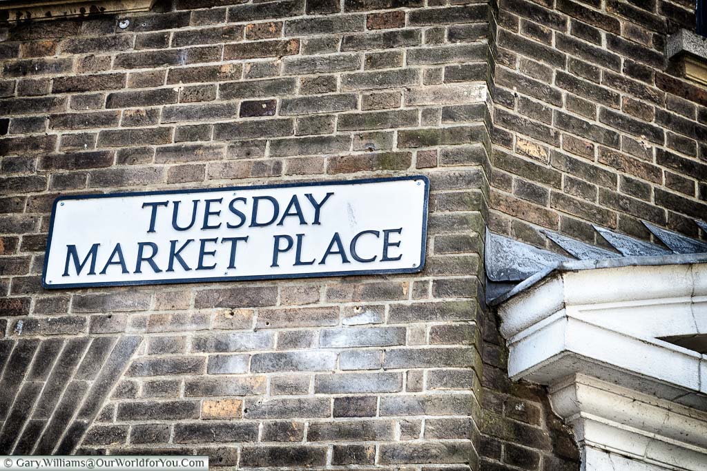 A traditional street sign for 'Tuesday Market Place' on an old brick-built building in King's Lynn, Norfolk