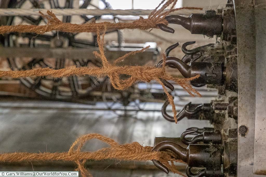 A close-up of the iron hooks with ropes attached to the spinning head of a rope making machine.