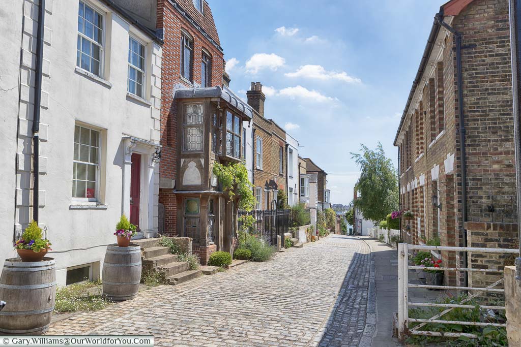 The cobbled high street, lined with historic brick-built houses, leading towards the River Medway on a sunny day.