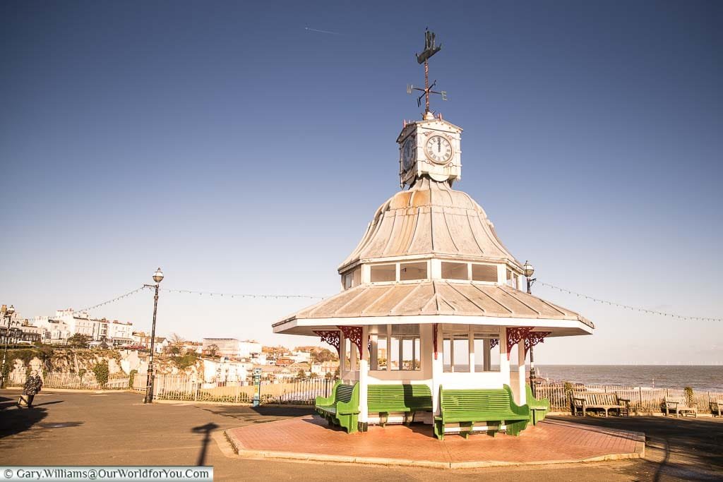 The seating shelter in Victoria gardens that also doubles as a clock tower with a weathervane on shaped like a sailing ship.