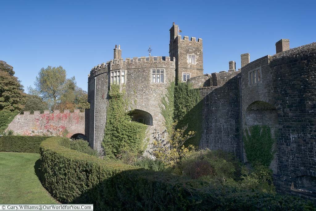 The view of Walmer Castle from its moat with climbering plants attached to its brickwork under a clear blue sky