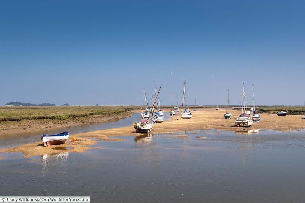 Small boats on the sand at Wells-next-the-Sea at low-tide under a beautiful blue sky in Norfolk