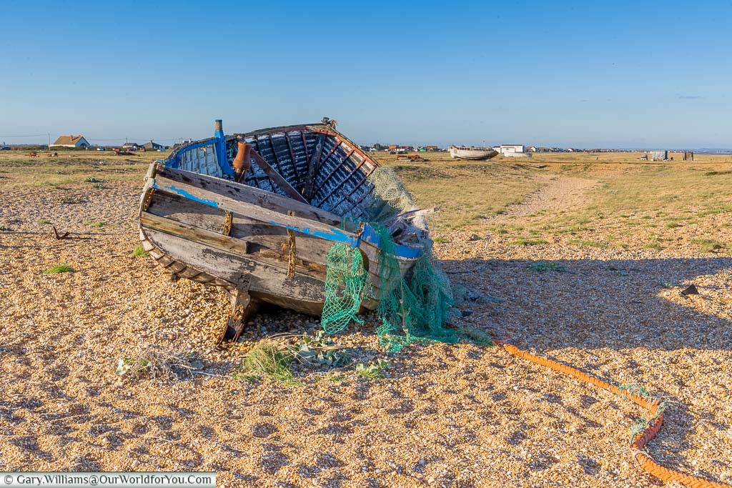 The remains fisherman's wooden trawler draped with fishing nets on the beach of Dungeness.