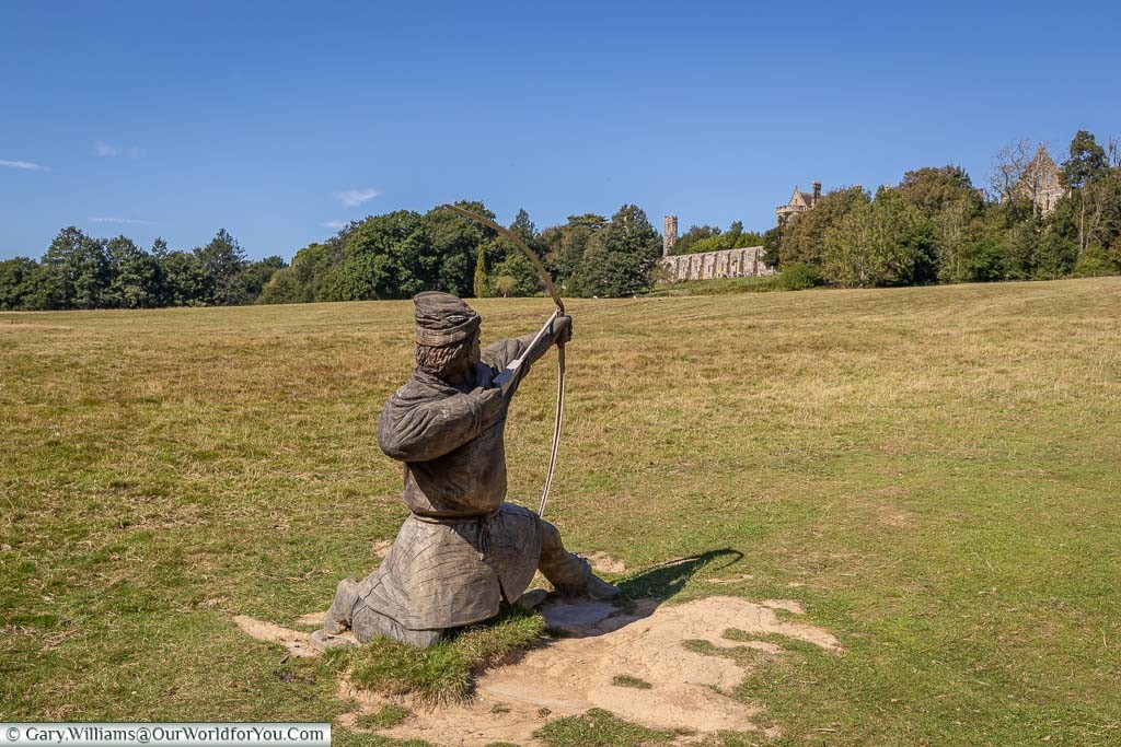 A wooden statue of a kneeling archer aiming in the direction of the Abbey from the edge of the battleground.