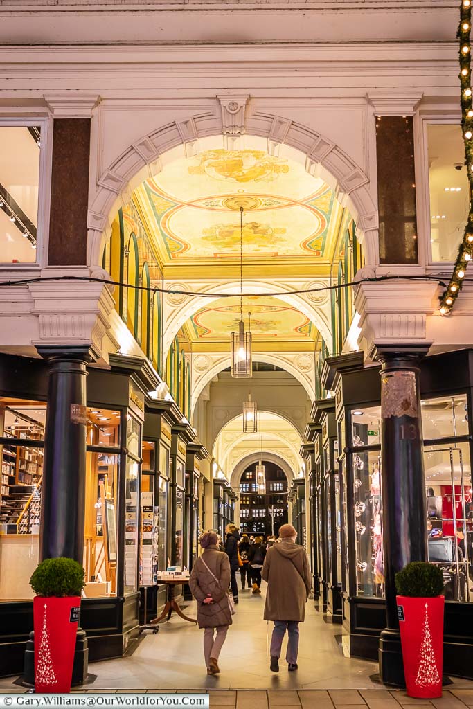 A passage off Neuer Wall in Hamburg with an ornately decorated ceiling and rows of sophisticated shops lining either side.