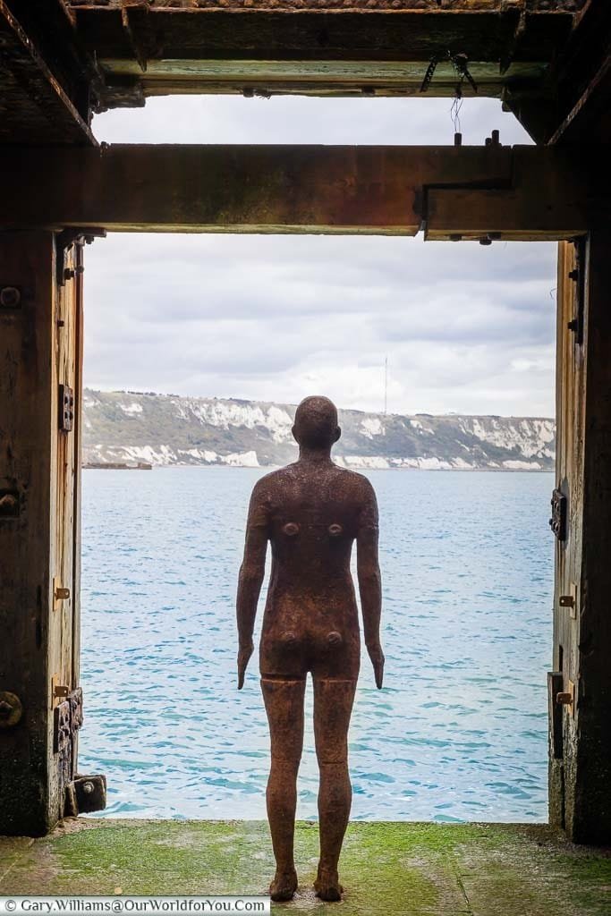 Looking from behind the Antony Gormley installation "Another Time XVIII” in the harbour arm onto the water and the white cliffs.