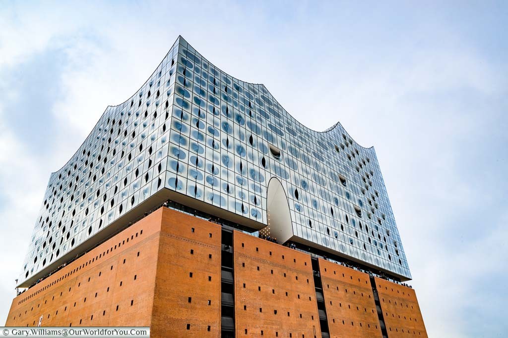 The Elbphilharmonie from ground level looking at the red brick base and the unique glass upper levels of this impressive concert hall.