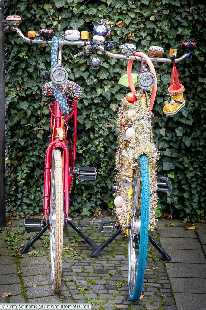 Two traditional bicycles decorated with baubles, tinsel and other ornaments parked up on their stands on the street side. Münster has German's capital of bicycles with more bikes than people.