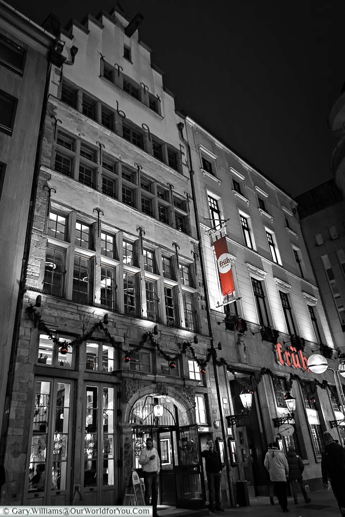 The front of the Früh am Dom brewhouse in black and white with the red of the Früh logo the only colour in the image.