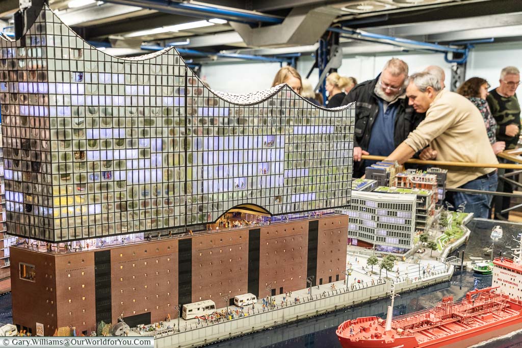 A scale model of the Elbphilharmonie at Miniatur Wunderland, with visitors inspecting the level of detail in the exhibit.