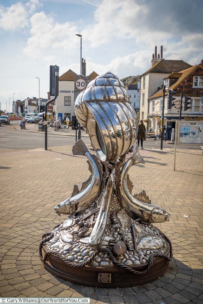 A polished steel sculpture of a giant winkle (sea snail) supported by fish at the point the old town of Hastings meets Rock-a-Nore