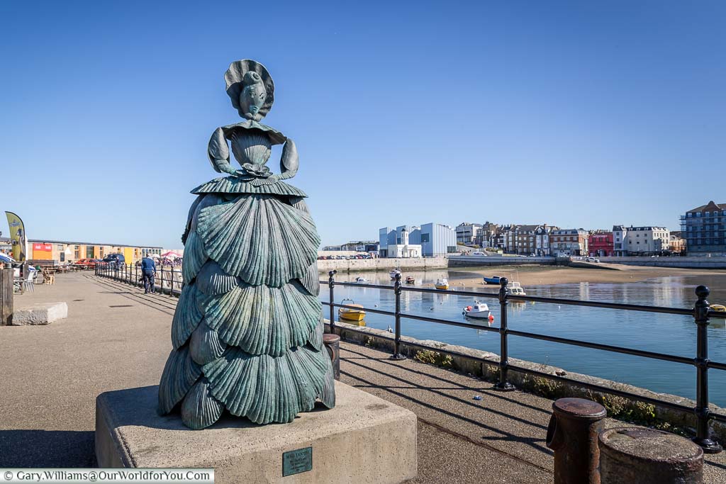 A bronze statue of a woman made of shells, known as 'The Shell Lady of Margate' by Ann Carrington at the end of the Harbour Arm in Margate's Old Town.