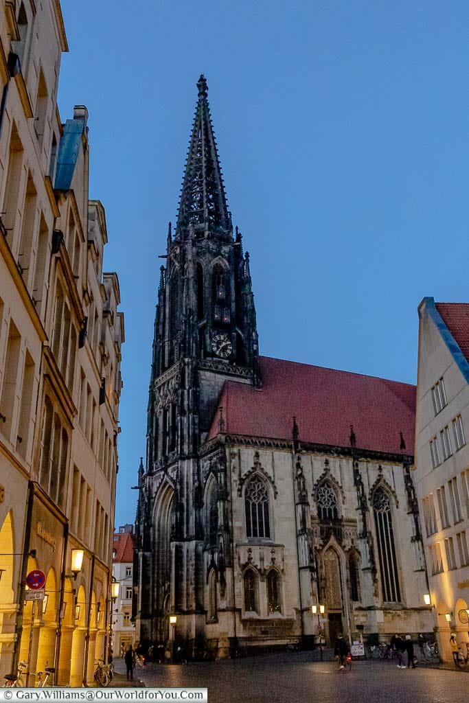 The St. Lamberti Church at dusk. Close inspection shows the 3 lights installed in the Anabaptists cages attached to the spire, above the clock.