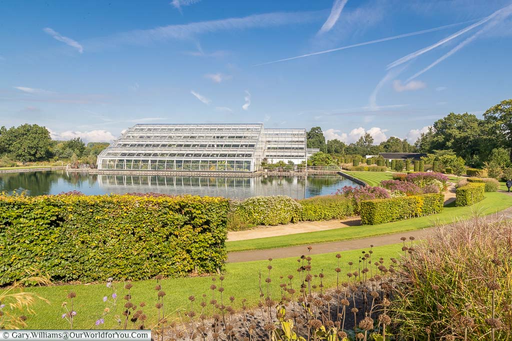 A view of the Glasshouse across the lake from the borders around it.
