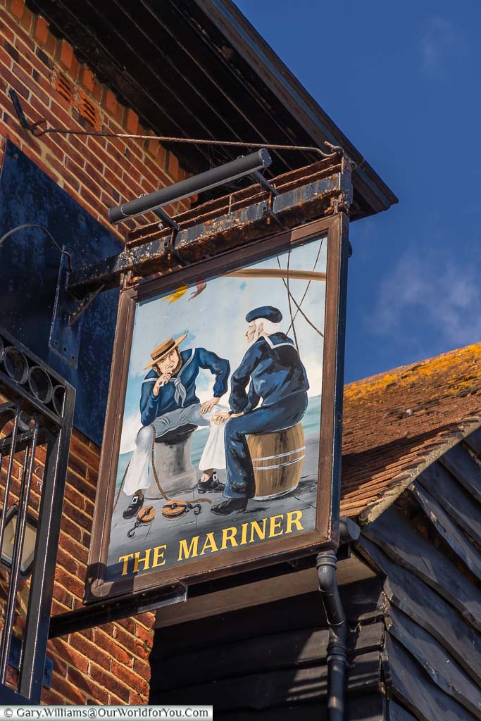 The Mariner pub sign depicting two sailors seated by the edge of the harbour in conversation.