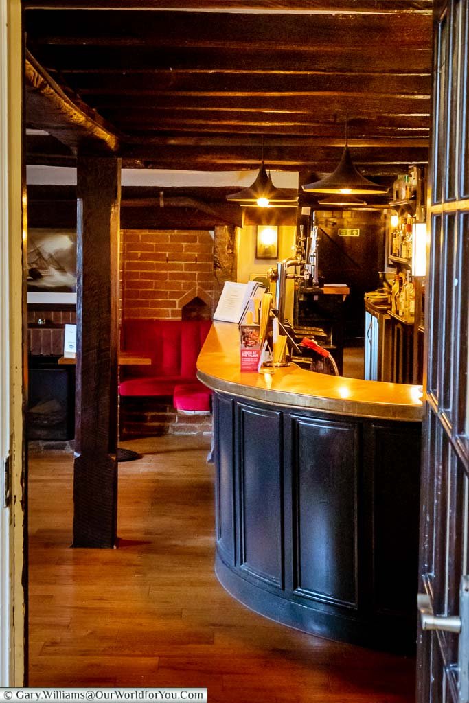 Looking through the dining room door to a view of the traditional copper-topped bar under the open beam ceiling.