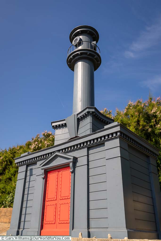 An elaborate blue-grey beach hut with a bright red door in an 18th Century Baroque style.