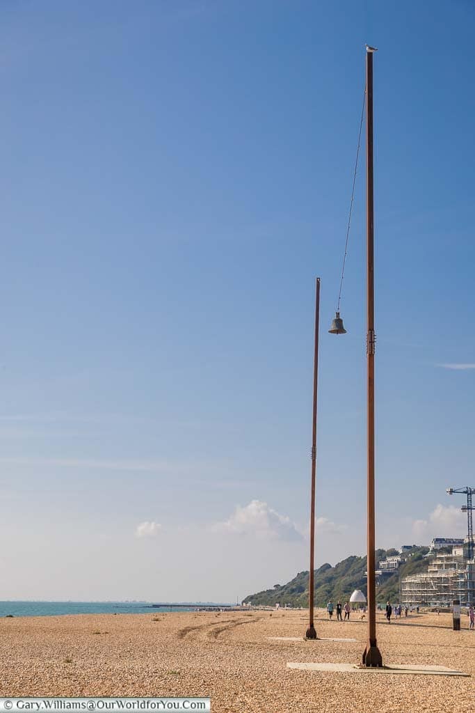 A single church bell suspended between two 2 20 metre steel pillars on Folkestone Beach as part of Creative Folkestone
