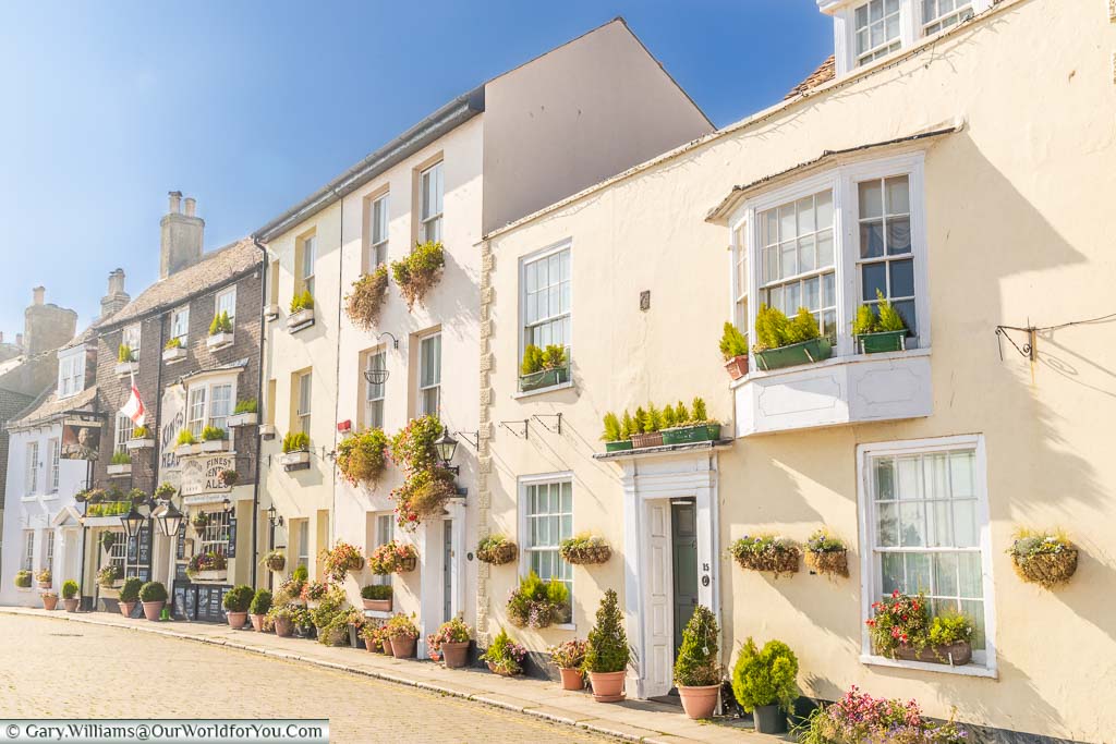 The pastel-coloured buildings decorated with potted plants & window baskets of beautiful Beach Street in Deal, Kent