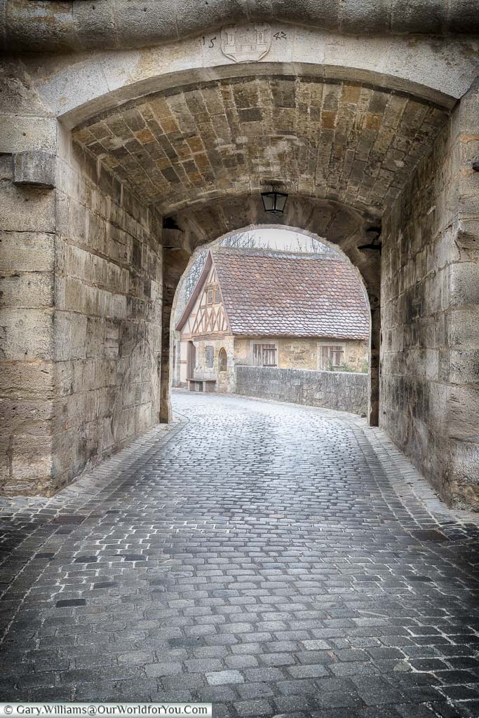 Looking along a cobbled lane on a through an archway on a frosty day. This is one of the routes into Rothenburg ob der Tauber.