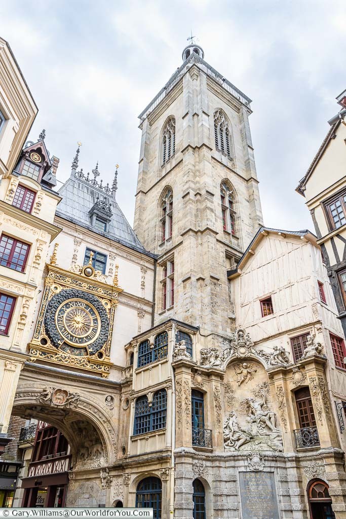 Rouen's famous Gros-Horloge.  An ornate, gold-trimmed,  clock mounted above an arch in one of the old town's thoroughfares next to a stone belfry.