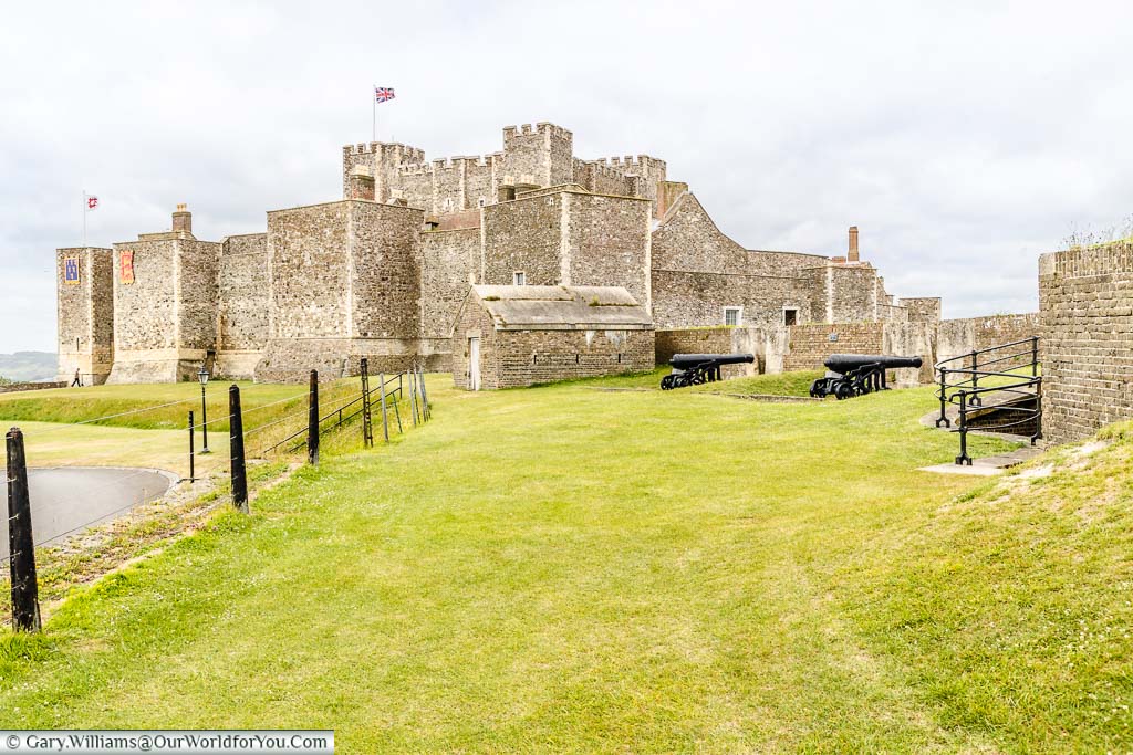 A view of Dover Castle from the grass banks that surround it. There are some cast iron Napoleonic cannons set defensive positions in the foreground.