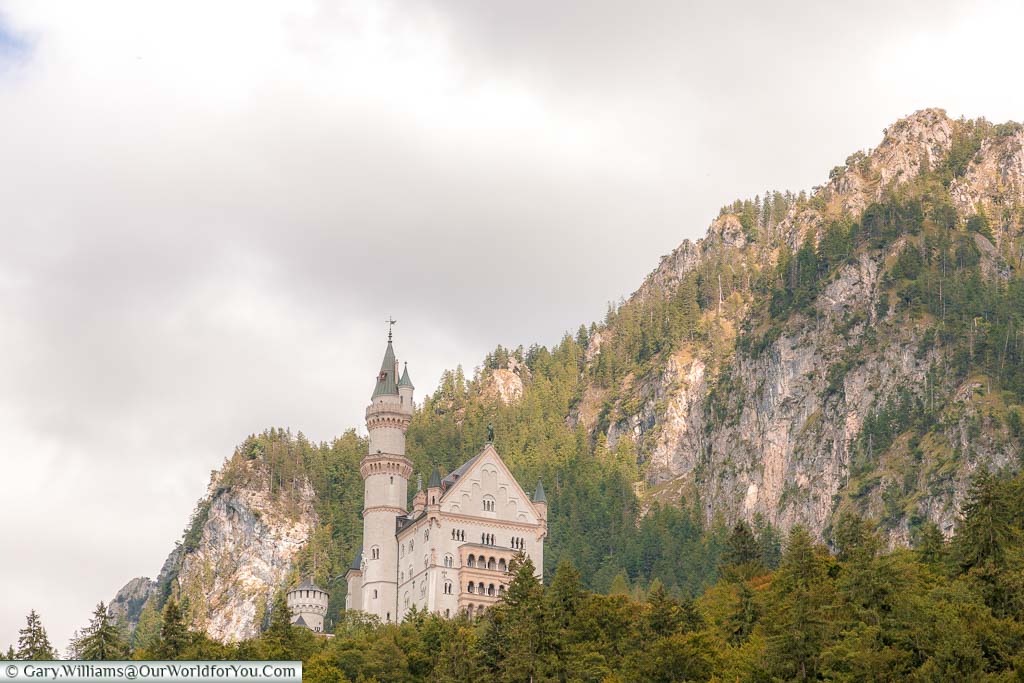 Looking up at Schloss Neuschwanstein against a backdrop of the wooded mountains of Bavaria.