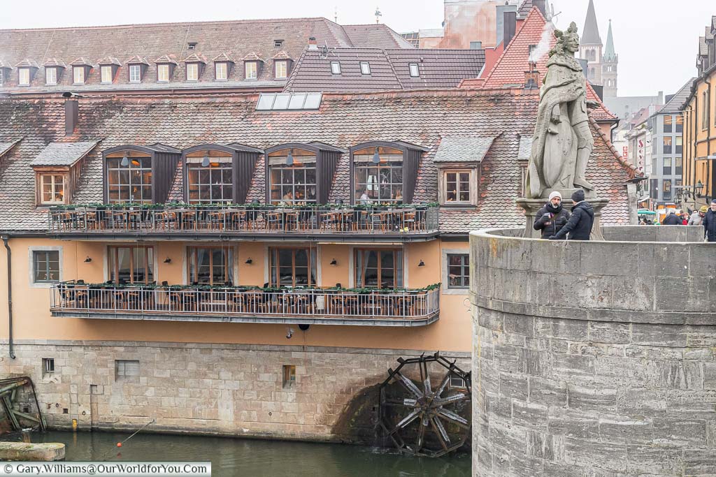 Looking across from the old main bridge in Würzburg to a riverside restaurant with a waterwheel dipping into the river.