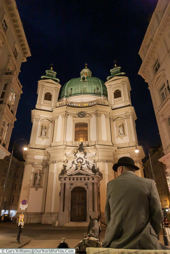 The view from the back of a horse-drawn carriage, at night, in front of Saint Peter's Church in the centre of Vienna