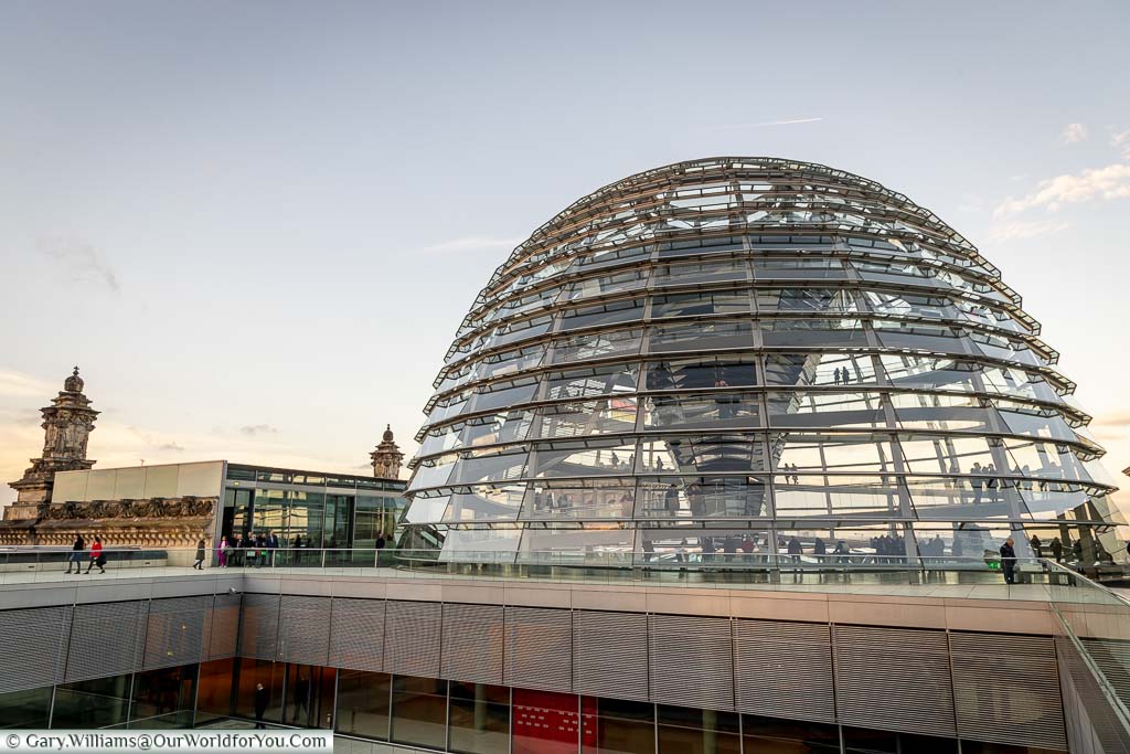 The view of the glass dome of the Reichstag in Berlin from the far corner of the rooftop walkway in the evening light.