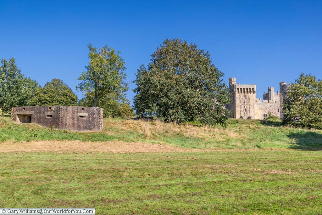 A brick-built Second World War pillbox with Bodiam Castle in the background