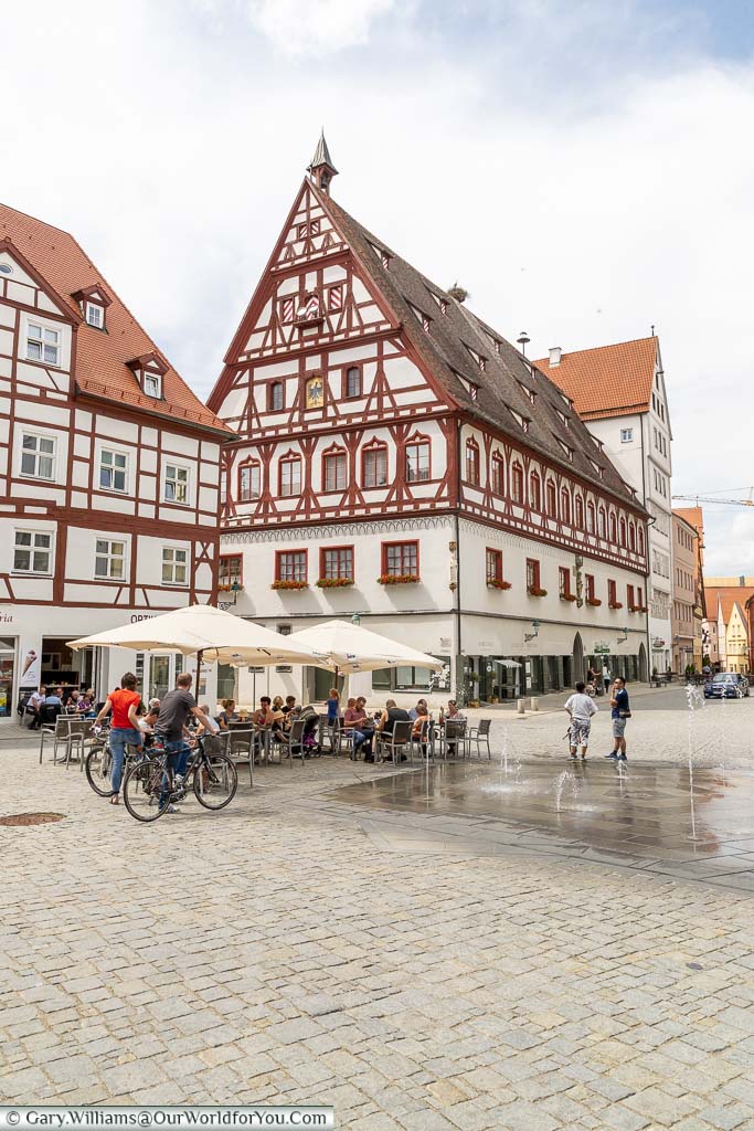 The pedestrianised centre of Nördlingen with water jets erupting in front of a cafe against the backdrop of a historic, half-timbered, building