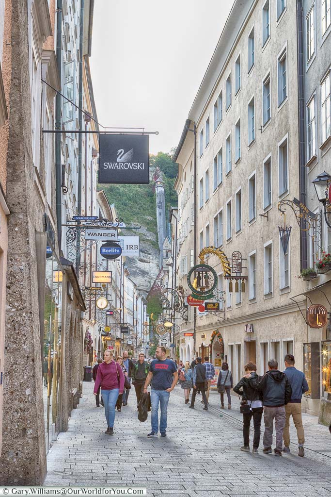Walking along shopping street in central Salzburg, Each shop displays its own shop sign from an wrought iron sign holder.