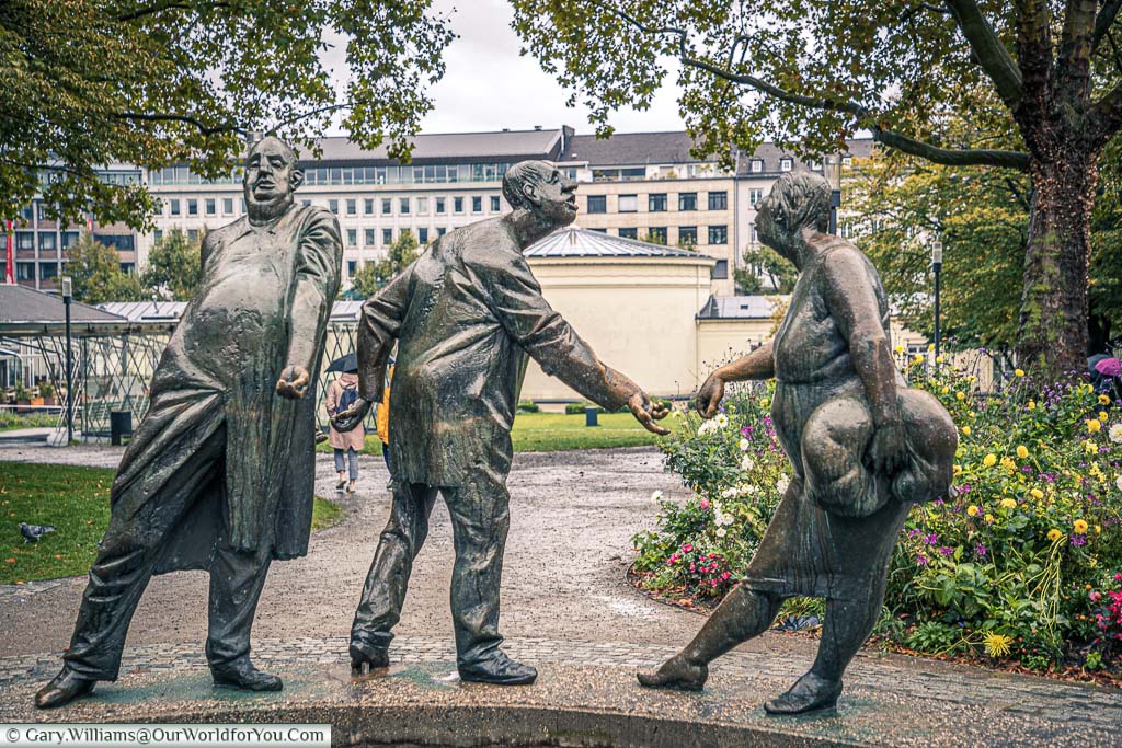3 brass statues that make up part of the ‘Circle of Money fountain in Aachen , Germany. The first figure is the banker taking money with one hand and transferring it out round his back with another, the second figure is taking that money in one hand and passing on to his wife with his other hand.