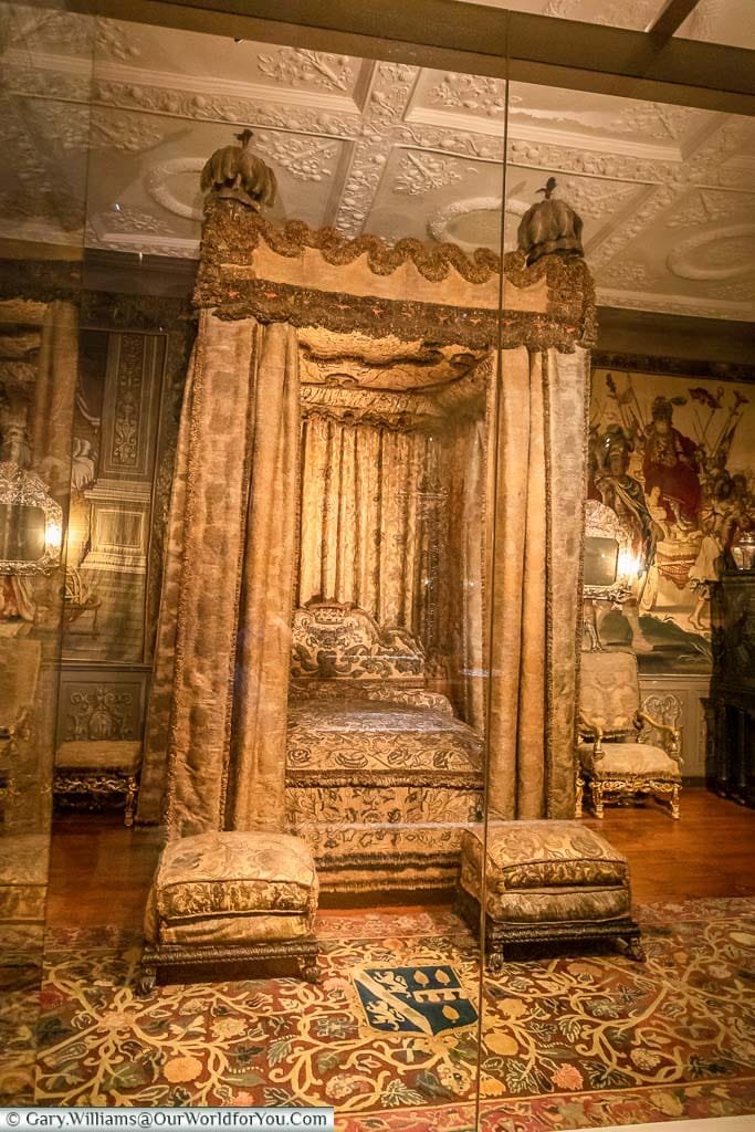 An ornate four-poster bed, with golden drapes, in the King's Bedroom within Knole House