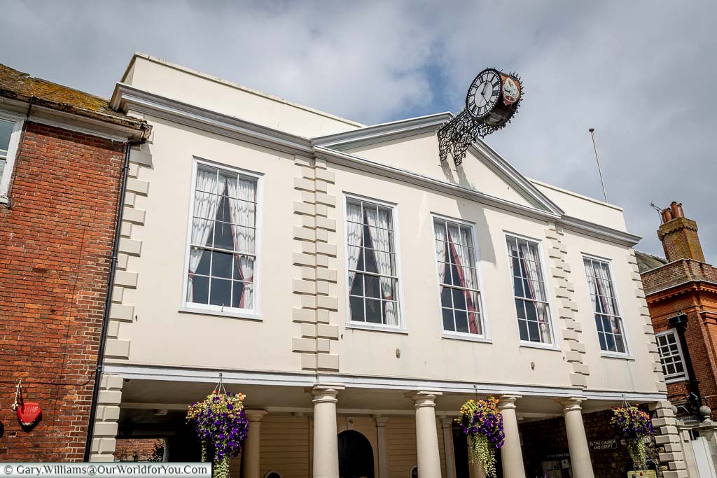 A clock protruding from the historic collonaded town hall in Hythe, Kent