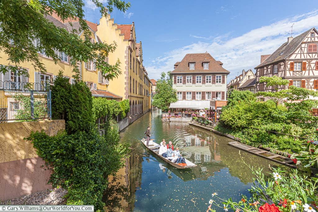 A family group enjoying a boat trip on the canals around Colmar in the Alsace region of France on a bright sunny summers day